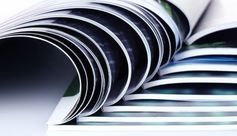 Nahaufnahme von aufgefächerten Seiten eines Hochglanzmagazins oder Katalogs mit Fokus auf die geschwungenen Papierkanten